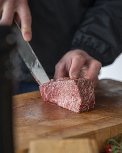 rohes Wagyu-Fleisch auf einem Holzbrett in Tranchen schneiden, Zubereitung und Rezepte